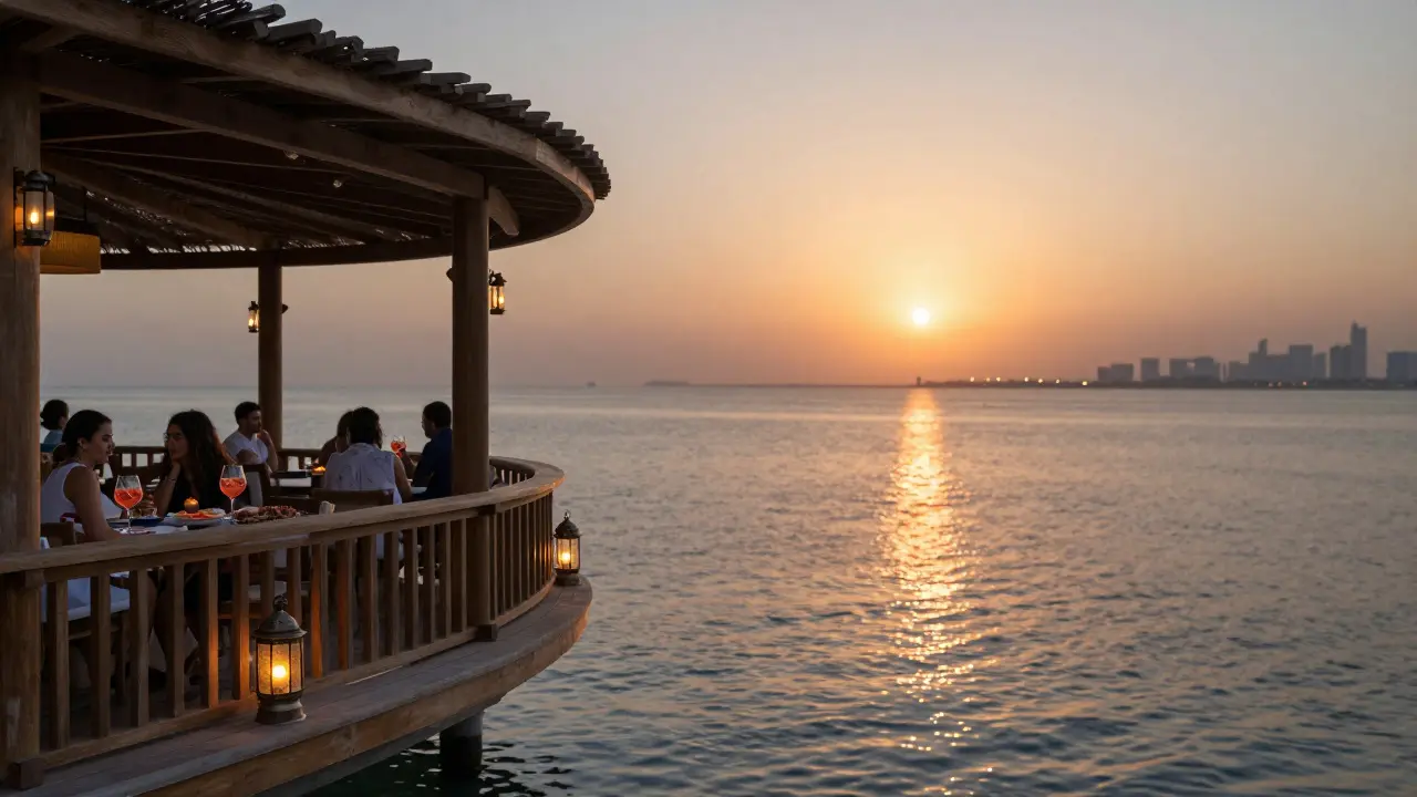 Zuma Dubai terrace at dusk with wooden decking, glowing lanterns, and sunset reflections on water.