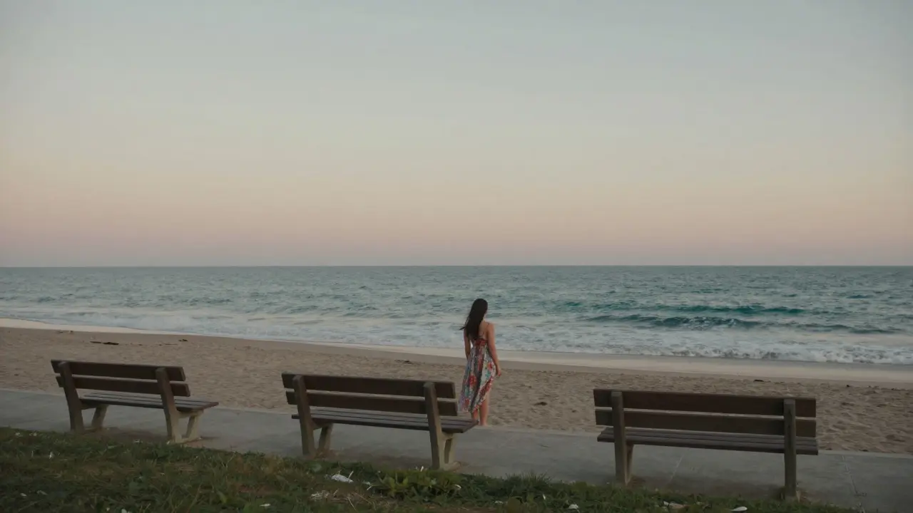 A lone figure standing on a quiet beachwalk at La Mer as the sun sets over the water.